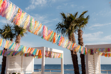 Multicolored garlands fringe with tassels on a summer beach playground.