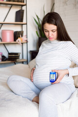 Pregnant woman holding glucose meter with result of measurement sugar level, concept of diabetes...