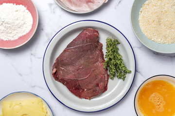 Preparation of traditional Milanese escalope with flour, egg, breadcrumbs, cheese and ham