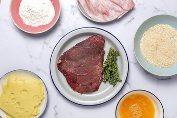 Preparation of traditional Milanese escalope with flour, egg, breadcrumbs, cheese and ham