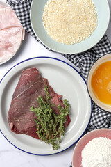 Preparation of traditional Milanese escalope with flour, egg, breadcrumbs, cheese and ham