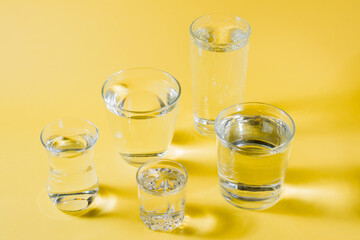 Several glasses of water of different shapes in a yellow-gray palette. Concept of inclusiveness and compatibility.