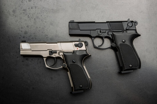 Two pistols, black and silver on a metallic gray background. Short-barreled weapon for defense.