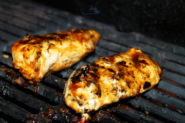 Close-up of chicken breast cooking on a barbecue grill.