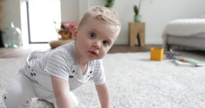 Cute curious baby boy following and touching camera indoors 50fps
