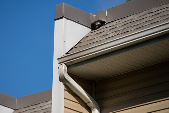 New rain gutter on a home against blue sky roof wall
