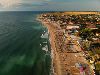 Aerial view of amazing beach with umbrellas and turquoise sea at sunrise. Black Sea at Vama Veche, Romania - obrazy, fototapety, plakaty