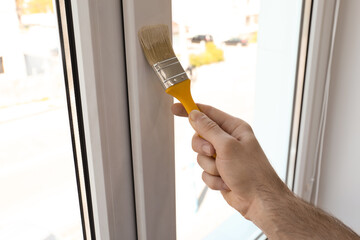 Man painting window frame at home, closeup
