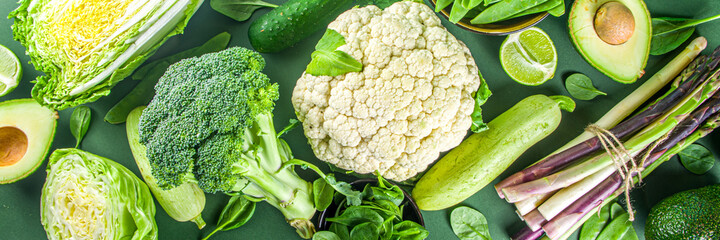 Healthy Diet Spring food background. Assortment of fresh raw organic green vegetables - broccoli, cauliflower, zucchini, cucumbers, asparagus, spinach, avocado, cabbage set on dark green background