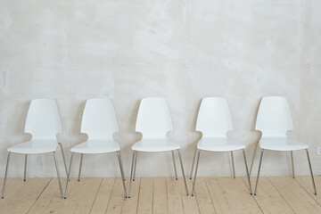 Row of white chairs near wall