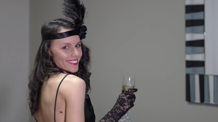 Portrait of vintage styled attractive woman dressed in Great Gatsby era (Roaring twenties) with pearl necklace and lace gloves racing glass of champagne on a themed party
