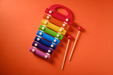 Multicolored xylophone on orange background, top view