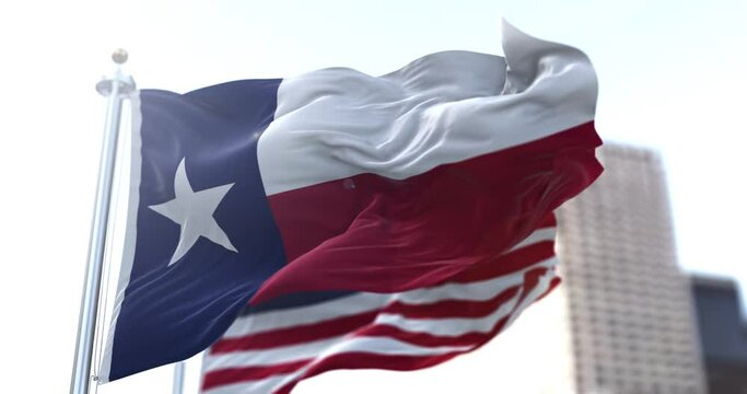 The Texas state flag flapping in the wind with the American national flag blurred in the background