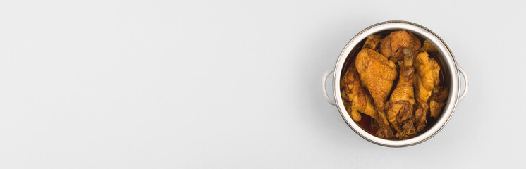 Banner fried cooked chicken in a saucepan on white silver flat lay background, a place to cook kitchen concept, dish for family, top view photo