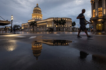 Old car on streets of Havana with Capitolio building in background with reflection on rain time. Cuba
