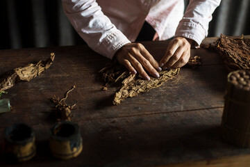 Hands of a woman rolling a cuban cigar in a beautfiul ambient. Vinales, Cuba