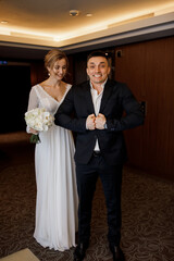 Romantic meeting of the bride and groom in the hotel corridor. The groom gives the bride a wedding bouquet of white roses. Morning before the wedding.