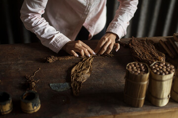 Hands of a woman rolling a cuban cigar in a beautfiul ambient. Vinales, Cuba - obrazy, fototapety, plakaty