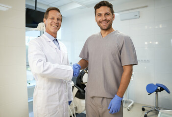 Two male colleagues shaking hands at dental clinic