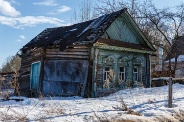 Old blue crooked wooden house in early spring or winter. Side view. Kostroma region, Russia