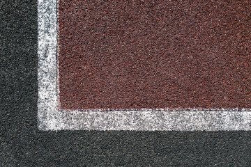 Corner of rubber-covered sports field with white markings. Textured background.