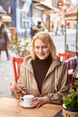 Street cafe in Turkish Istanbul, young smiling woman drinking coffee at table in winter.