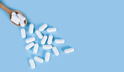 Pharmaceuticals, medicine and healthcare. White pills on a blue background. Baner. Top view. Copy space. Close-up.