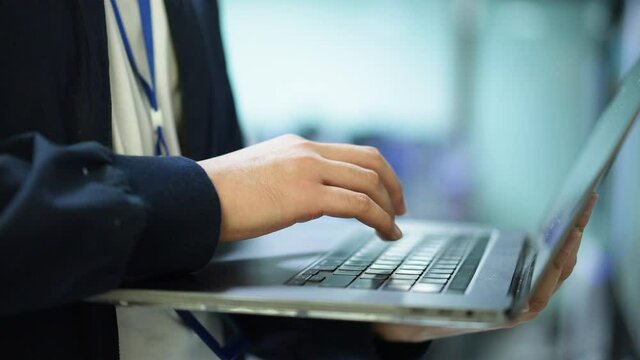 slow motion scene on network engineering man hand typing keyboard laptop to configure command software and check connectivity on ethernet broadband at data center operation room for technology concept