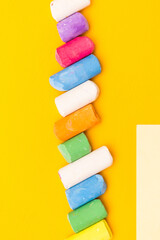 Children's drawing crayons lie in a row on a yellow background.