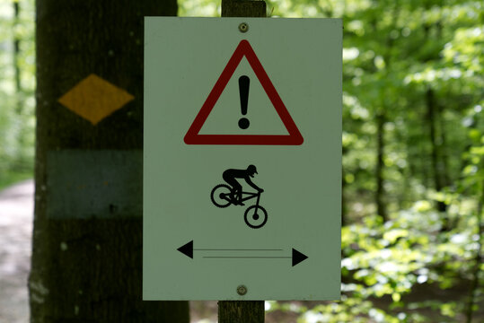 Traffic sign watch out for mountain bike cyclists at mountain bike trail in the woods. Photo taken May 18th, 2021, Zurich, Switzerland.