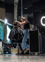 shot of hairdresser cutting hair of handsome guy client, Hairstylist serving client at barber shop