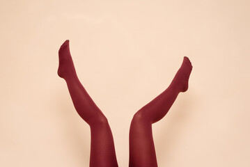 Woman raised up legs in the red stockings on the light background.
