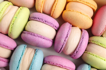 Many delicious colorful macarons on white background, top view