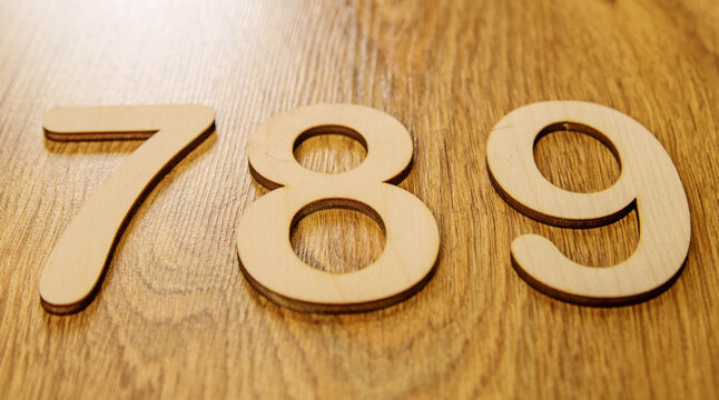 Flatley, side view of large wooden numbers seven, eight and nine lying in order on a wooden background