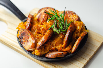 Traditional Polish dish called bigos made of sauerkraut, sausage and mushrooms, food served warm in a cast iron pan