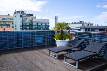 Fototapeta premium roof terrace with sun loungers behind a panoramic view of the city