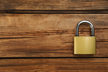 Fototapeta premium Modern padlock on wooden table, top view. Space for text
