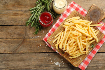 Delicious french fries served on wooden table, flat lay. Space for text