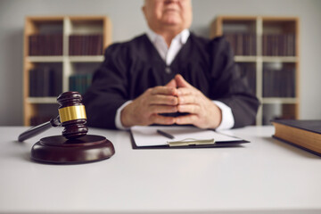 Close up of a dark brown wooden gavel lying on a sound block on a judges desk in the courtroom...