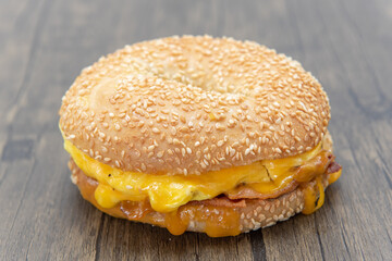 Sesame bagel bun envelops this egg and bacon breakfast sandwich dripping with melted cheese.