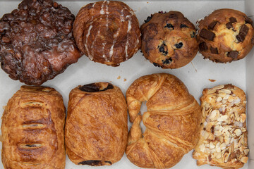 Variety of baked goods from the bakery ranging from apple fritter to croissants and muffins to eat.