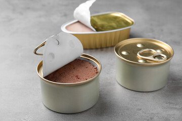 Tin cans of wet pet food on grey table