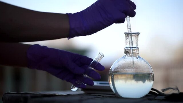 Well water pollution concept. Scientist is taking a water sample of garden well.