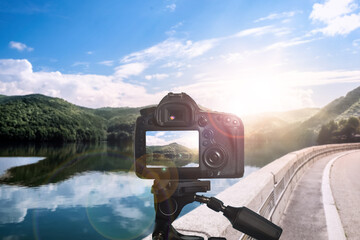 Taking photo of beautiful mountain landcape and road with camera mounted on tripod