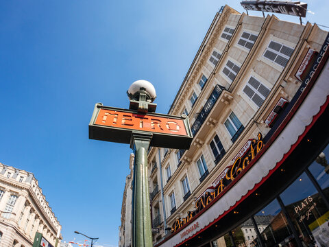 Paris, France - May 20, 2018: Ultra wide-angle view of French Haussmannian building on Rue du Faubourg Saint Denis with neon sign of Paris Nord Cafe and metro metropolitain vintage signage