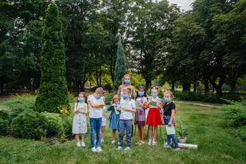Obraz premium A class of masked school children is engaged in outdoor training during the epidemic. Back to school, learning during the pandemic