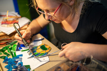 soldering the stained glass window, woman is making a stained glass, soldering the stained glass...
