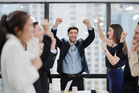 In a meeting room, a manager and his team are very happy with their team performance.