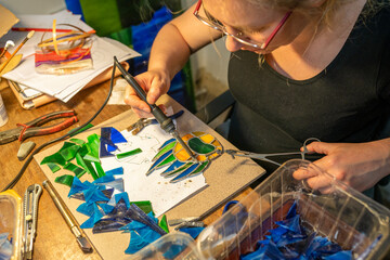 soldering the stained glass window, woman is making a stained glass, soldering the stained glass window