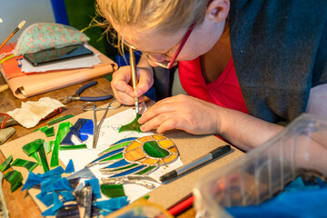 soldering the stained glass window, young woman is making a stained glass, stained glass crafting, 
